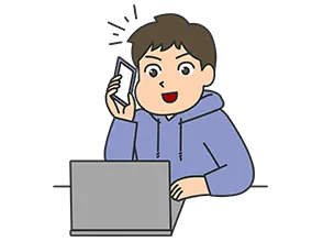 パソコンを見ながら電話をかける、パーカーを着た男性
