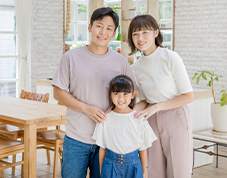 写真付きのお客様の声の良い例。新築一戸建てのリビングで、笑顔で肩を並べる父親、母親、娘の3人家族の記念写真