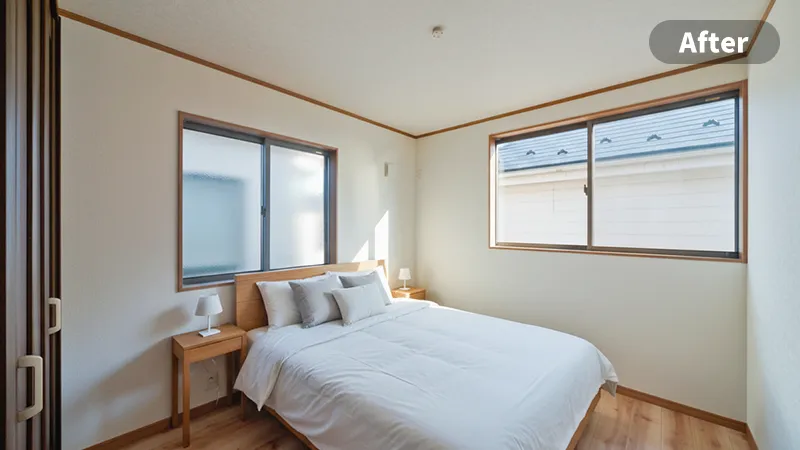 寝室のステージングアフター画像　壁にベッドの上の方が付く形でダブルベッドが置かれ、その横にサイドテーブルと小さなライトが配置されている